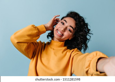 Pleased girl in dental braces taking selfie. Studio shot of gorgeous woman in yellow sweatshirt. - Shutterstock ID 1511281598