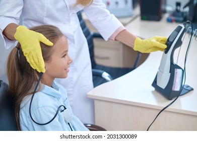 Pleased Girl Having Her Hearing Checked On The Audiometer