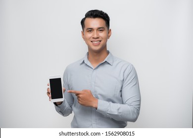 Pleased Happy Young Asian Man Holding Smartphone Pointing At Cellphone Screen As Showing Awesome New Phone