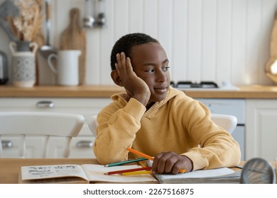 Pleased kid boy distracted from study lost in thoughts about play computer game instead of learn lessons. Dreaming bored child schoolboy sit at table feel unmotivated self explore textbook at home  - Powered by Shutterstock