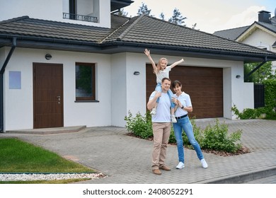 Pleased mother and daughter on father's shoulders in front of new townhouse - Powered by Shutterstock