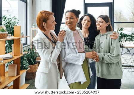 pleased psychologist looking at overjoyed african american woman near multiethnic girlfriends during motivation session in consulting room, female unity and support concept
