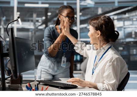 Pleased server farm manager does high five with employee after completing operations. Cheerful supervisor praising technician accomplishments in data center after checking performance report