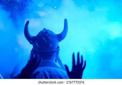 A Pleased Tall Man Backs In A Cap With Horns In The Smoke From Co2