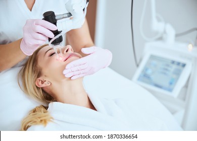 Pleased young Caucasian female undergoing the fractional carbon dioxide laser treatment in a beauty clinic - Shutterstock ID 1870336654