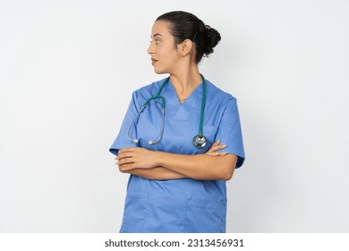 Pleased Young doctor woman wearing blue uniform over isolated background keeps hands crossed over chest looks happily aside - Powered by Shutterstock