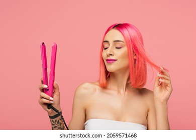 Pleased Young Woman With Colorful Hair Holding Hair Straightener Isolated On Pink