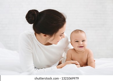 Pleasure. Adorable Baby Taking Sun Bath, Lying On Bed With Mommy, Free Space