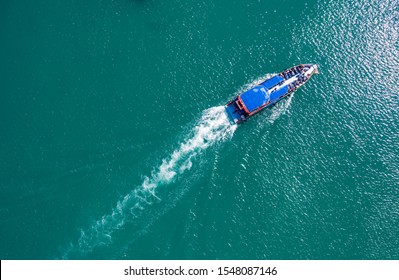 Pleasure Boat With Tourists On Board Floating In The Sea, The Trail With Waves Behind, Top View From The Drone