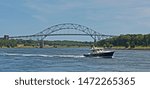 A pleasure craft passes through the Cape Cod Canal in Massachusetts with the Sagamore Bridge in the background.