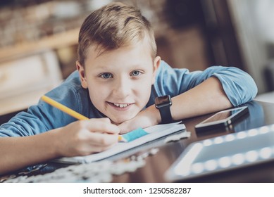 Pleasure emotions. Delighted boy keeping smile on his face and making notes
