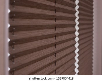 Pleated blinds Cosiflor close up on the window in the interior. Home blinds - cordless pleated modern shades on apartment windows. Brown color fabric.