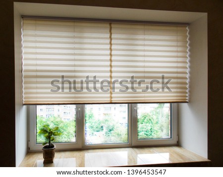 Pleated blinds XL, beige color, with 50mm fold closeup in the window opening in the interior. Home blinds - modern bottom up privacy shades half raised on apartment windows.           