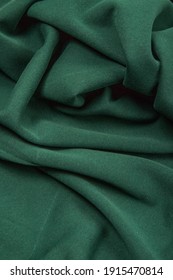 Pleats on fabric, knitted material of green color, folds