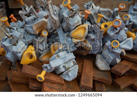 Plenty of container twistlocks lying on a bunch of rusty steel stoppers. Container lashing concept.