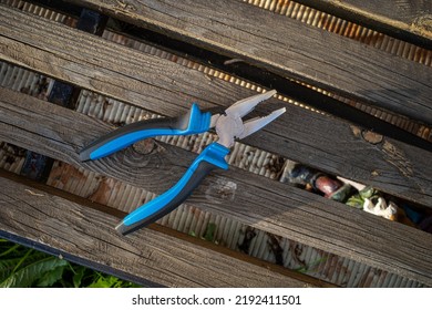 Pliers With A Blue Handle On A Wooden Bench Top View. Copy Space.