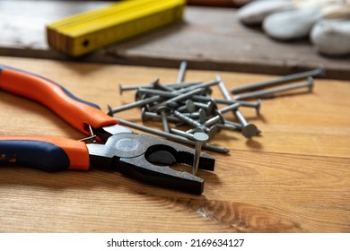 Pliers And Nail Stack On Wood. Carpenter Work Bench Table, Closeup View, Joinery Workshop