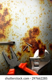Pliers, screwdriver and spanner on rusty background