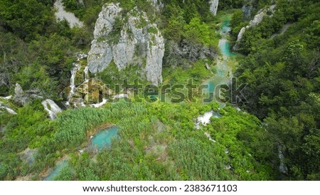 Plitvice waterfalls in mountain landscape of Croatia. Blue and green can be seen in the cascades. Water streams flow into a lake.