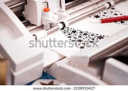 plotting machine makes large christmas stickers arranged from star symbols out of black adhesive vinyl film. DIY holiday gift and advertisement concept. selective focus