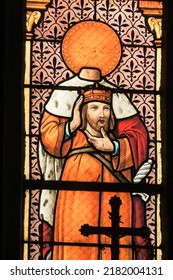 PLOUMILLIAU, FRANCE - Aug 9, 2018: Stained Glass Window Depicting Saint Milliau Of Cornwall Holding His Beheaded Or Decapitated Head Inside The Church