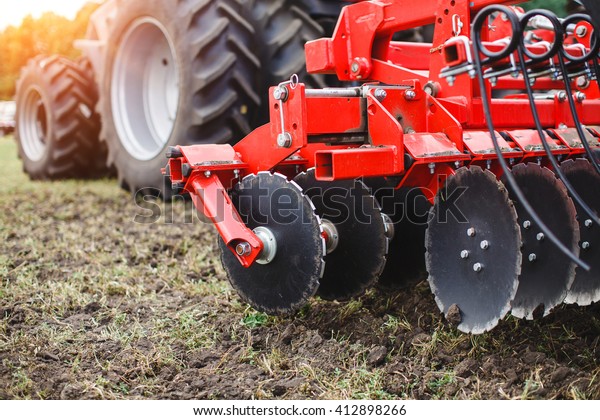 Plow modern tech red tractor close up on an\
agricultural field.\
Mechanism.