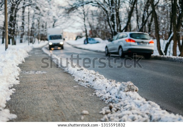 Plowed snow on footpath by vehicles moving on road\
during winter 