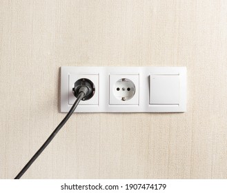 The Plug Is Plugged Into An Electrical Outlet On The Wall. Copy Space.