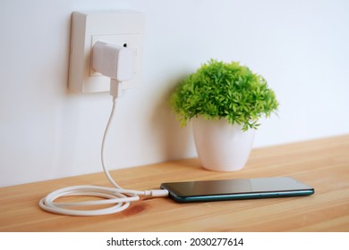 Plug in power outlet Adapter cord charger of smart phone on wooden floor - Shutterstock ID 2030277614