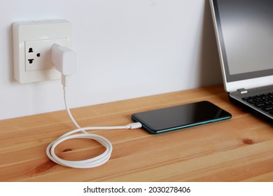 Plug in power outlet Adapter cord charger of smart phone on wooden floor - Shutterstock ID 2030278406