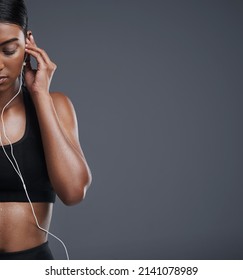 Plugged In, Now Lets Move. Studio Shot Of A Sporty Young Woman Listening To Music Against A Grey Background.