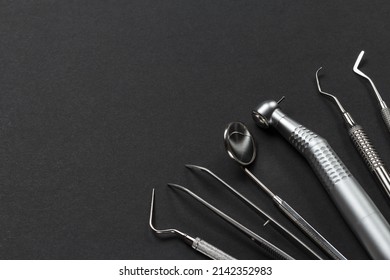 Plugger, tweezers, a mouth mirror, a dental handpiece with bur, a curette and a dental restoration instrument on the black background. Medical tools.