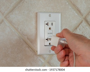 Plugging In Electrical Usb Cord And Charger Plug In Wall Outlet. Cell Phone Power Adapter Brick And Cord In GFCI Wall Plug.