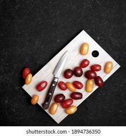 Plum Cherry Tomatoes And Knife On Cutting Board. Assorted Mini Cherry Tomatoes On Wooden Cutting Board. Scattered Red, Yellow And Black Plum Cherry Tomato On Black Grunge Background. - Powered by Shutterstock