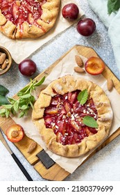Plum Galette. Healthy homemade wholegrain fruit pie (galette) with plums and almonds, vegan vegetarian dessert on a stone table. View from above.  - Shutterstock ID 2180379699