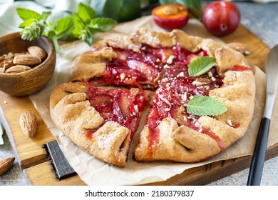 Plum Galette. Healthy homemade wholegrain fruit pie (galette) with plums and almonds, vegan vegetarian dessert on a stone table. 
