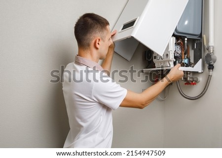 Plumber attaches Trying To Fix the Problem with the Residential Heating Equipment. Repair of a gas boiler