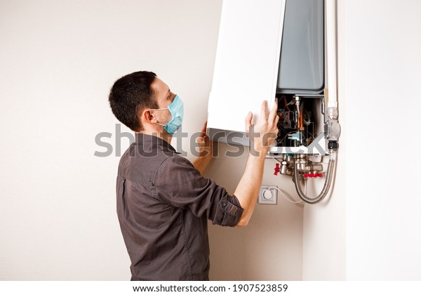 Plumber attaches Trying\
To Fix the Problem with the Residential Heating Equipment. Repair\
of a gas boiler