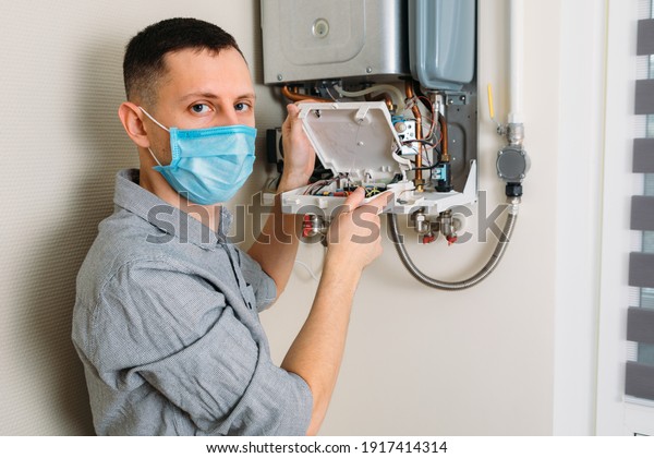 Plumber attaches Trying\
To Fix the Problem with the Residential Heating Equipment. Repair\
of a gas boiler