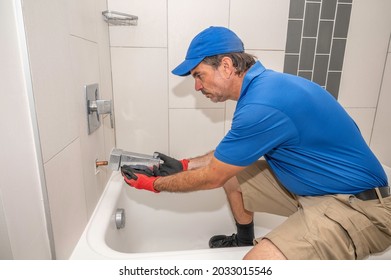 Plumber in bathtub removing or installing a tub spout faucet
