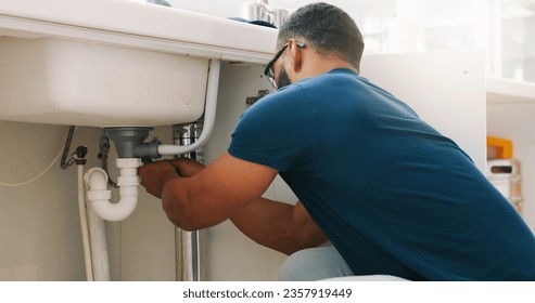 Plumber black man, kitchen and sink maintenance with tools, focus and pipe repair for drainage in home. Entrepreneur handyman, plumbing expert or small business owner in house for fixing water system - Powered by Shutterstock