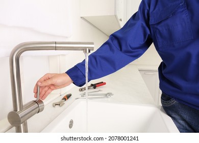 Plumber checking water flow from tap in kitchen, closeup. Repair service - Shutterstock ID 2078001241