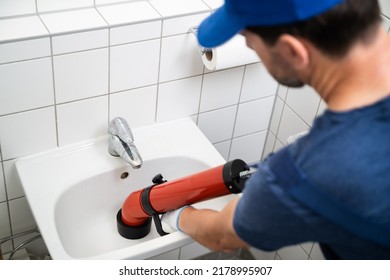 Plumber Cleaning Drain And Bathroom Sink Using Pump