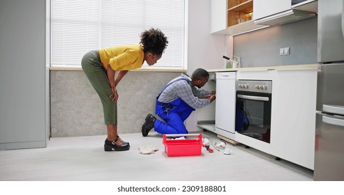 Plumber Cleaning Drain And Pipe In Kitchen - Powered by Shutterstock