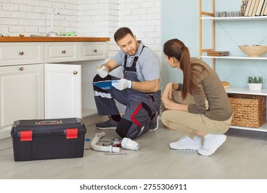 Plumber and client prepare estimate during maintenance service of sink or pipes in home kitchen, focusing on renovation in a professional setting with attention to detail and collaboration.