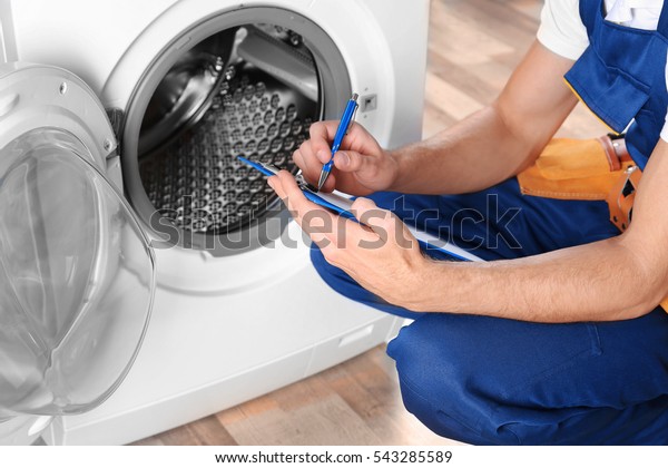 Plumber with\
clipboard near washing\
machine