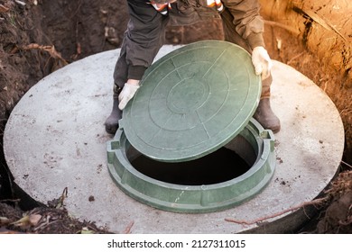 The Plumber Covers The Sewer Well With A Manhole Cover. Water Supply And Sewerage In A Residential Building.