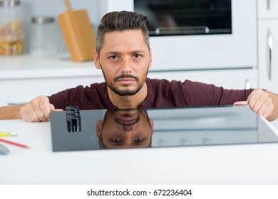 plumber crouching and taking notes in the kitchen