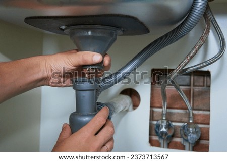 plumber disassembles the siphon under the sink,repair of plumbing in the kitchen, pipes clogged with dirt residues