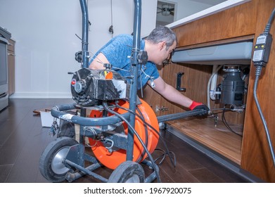 Plumber Drain Cleaning A Kitchen Sink Inside A Residential Home